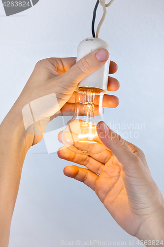 Image of hands with incandescent light bulb