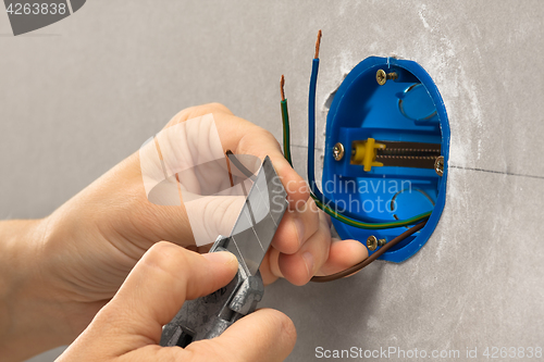 Image of hands of electrician striping the insulation of wires