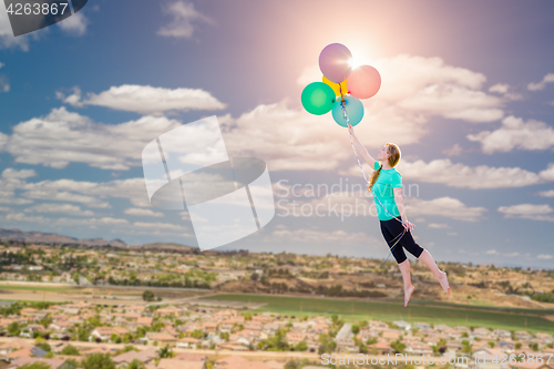 Image of Young Girl Being Carried Up and Away By Balloons That She Is Hol