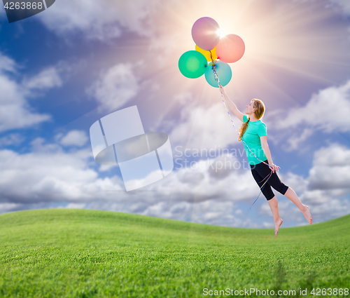 Image of Young Girl Being Carried Up and Away By Balloons That She Is Hol