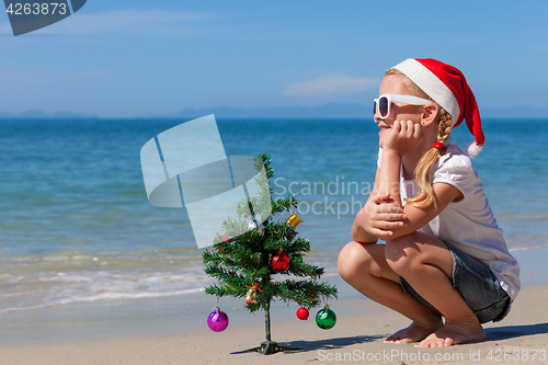 Image of Happy little girl sitting on the beach at the day time.