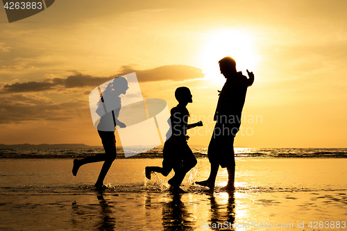 Image of Father and children playing on the beach at the sunset time.