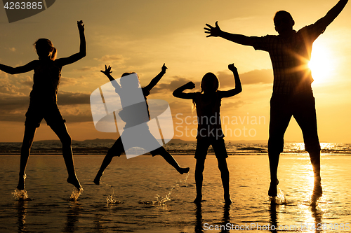 Image of Father and children playing on the beach at the sunset time.