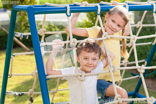 Image of happy brother and sister playing on the playground