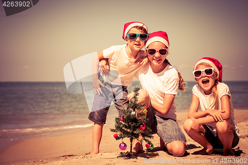 Image of Three happy children  playing on the beach at the day time.