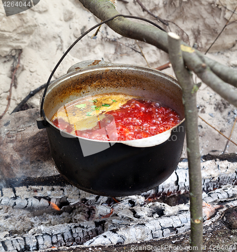 Image of Soup cooking in sooty cauldron on campfire 