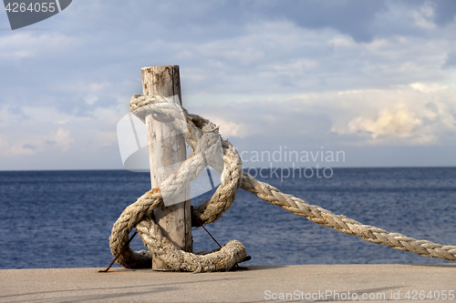 Image of Rope on seafront and cloudy sky in sun autumn day