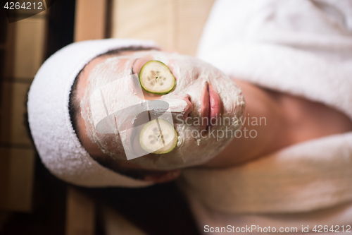 Image of woman is getting facial clay mask at spa