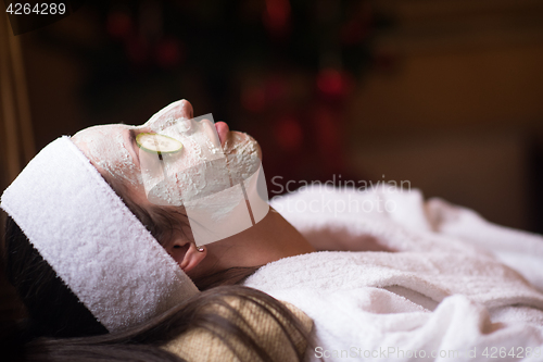 Image of woman is getting facial clay mask at spa