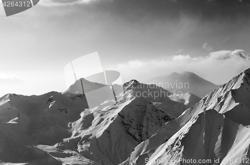 Image of Black and white view on snowy sunlight mountains in early fog mo