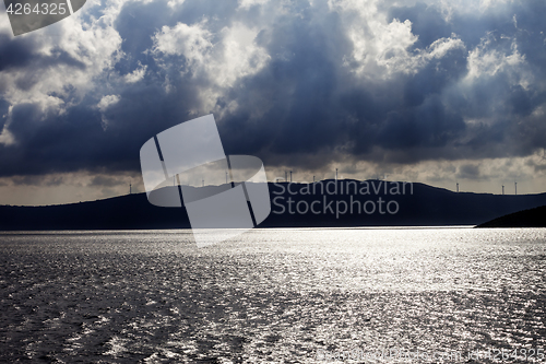 Image of Sunlight sea, wind farm on mountains and cloudy sky before storm