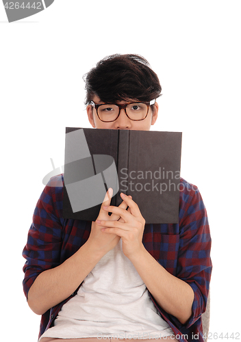 Image of Asian man holding book for face.