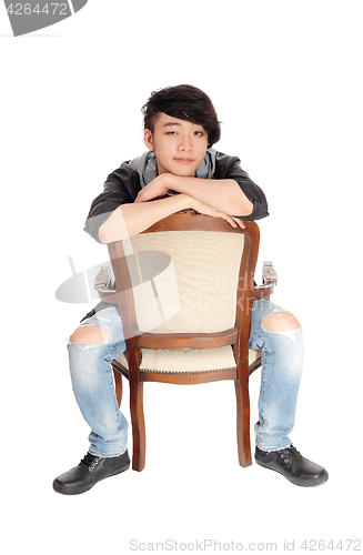 Image of Asian man sitting backwards on chair.