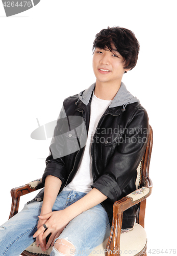 Image of Asian teenager sitting in old armchair.