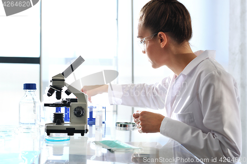 Image of Chemist examine the sample under a microscope.