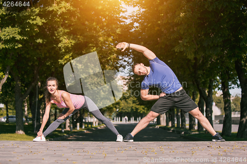 Image of Fit fitness woman and man doing stretching exercises outdoors at park