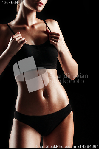 Image of Muscular young woman athlete on black