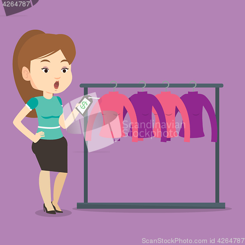 Image of Woman shocked by price tag in clothing store.