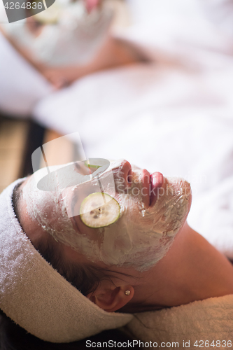 Image of woman is getting facial clay mask at spa