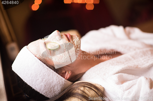 Image of woman is getting facial clay mask at spa