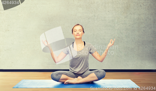 Image of woman making yoga meditation in lotus pose on mat