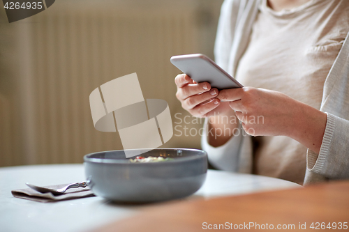 Image of woman with smartphone photographing food at cafe