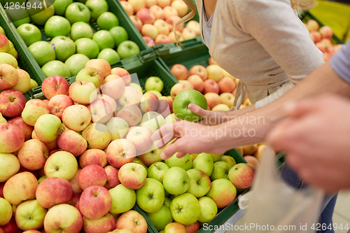 Image of happy couple buying apples at grocery store