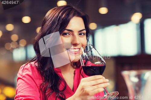 Image of smiling woman drinking red wine at restaurant