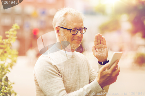 Image of senior man having video call on smartphone in city