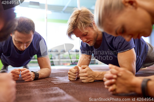 Image of group of people doing plank exercise in gym