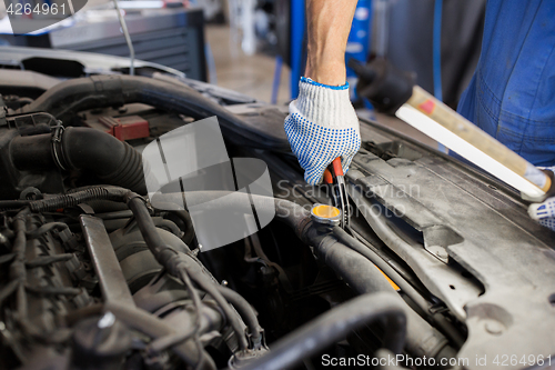 Image of mechanic man with pliers repairing car at workshop