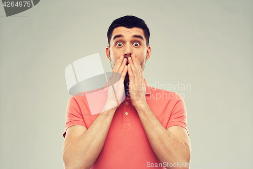 Image of scared man in polo t-shirt over gray background