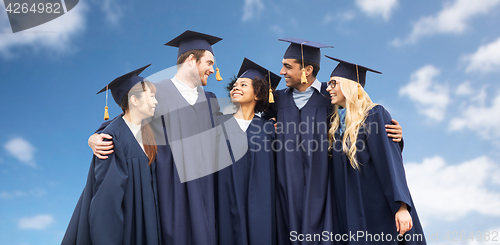Image of happy students or bachelors over blue sky