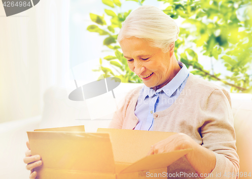 Image of happy senior woman with parcel box at home