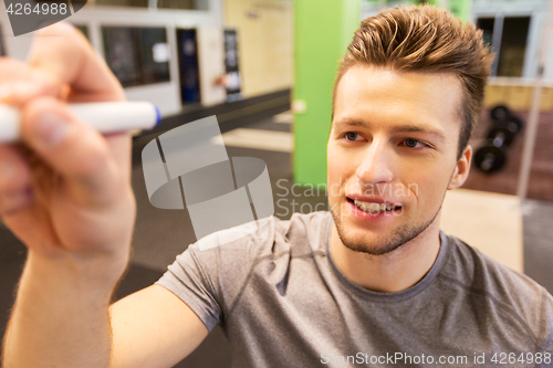 Image of happy young man with marker writing in gym