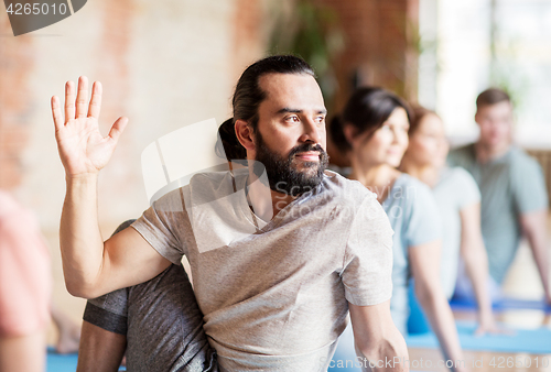 Image of man with group of people doing yoga at studio