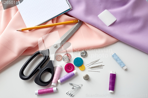 Image of scissors, sewing tools, cloth and notepad