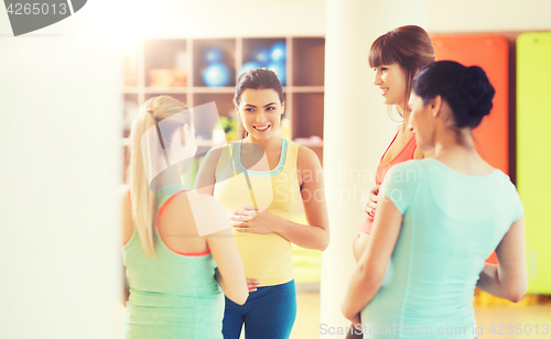 Image of group of happy pregnant women talking in gym