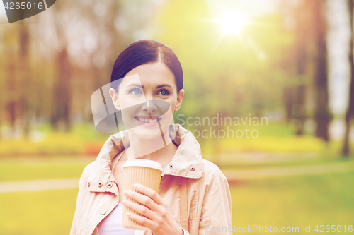 Image of smiling woman drinking coffee in park