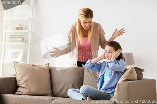 Image of girl closing ears to not hear angry mother at home