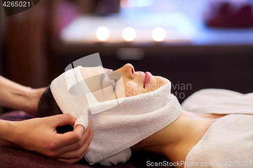 Image of woman having face massage with towel at spa