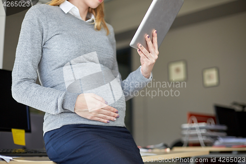 Image of pregnant businesswoman with tablet pc at office
