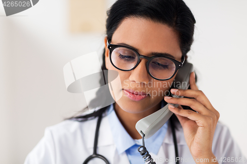 Image of doctor in glasses calling on phone at hospital