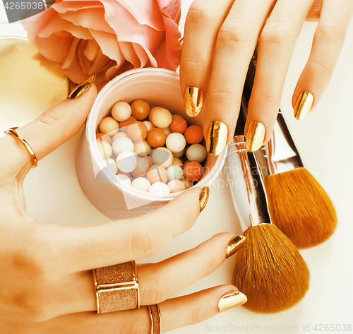 Image of woman hands with golden manicure and many rings holding brushes,
