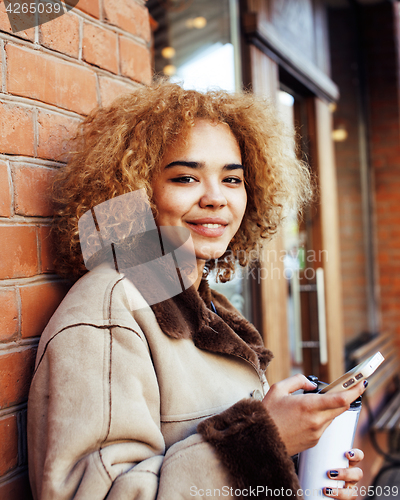 Image of young pretty african american women drinking coffee outside in c