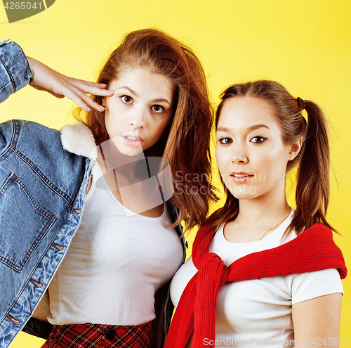 Image of lifestyle people concept: two pretty young school teenage girls having fun happy smiling on yellow background 