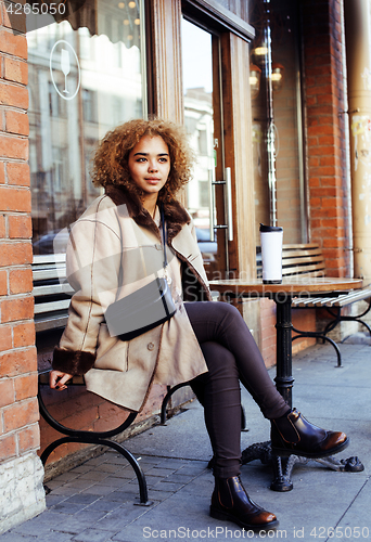 Image of young pretty african american women drinking coffee outside in c