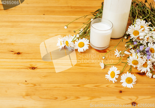 Image of Simply stylish wooden kitchen with bottle of milk and glass on table, summer flowers camomile, healthy foog moring concept