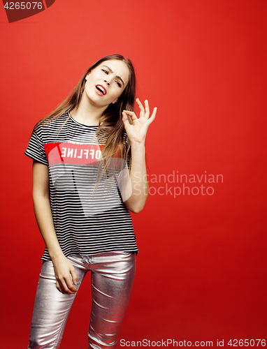 Image of young pretty emitonal posing teenage girl on bright red background, happy smiling lifestyle people concept 