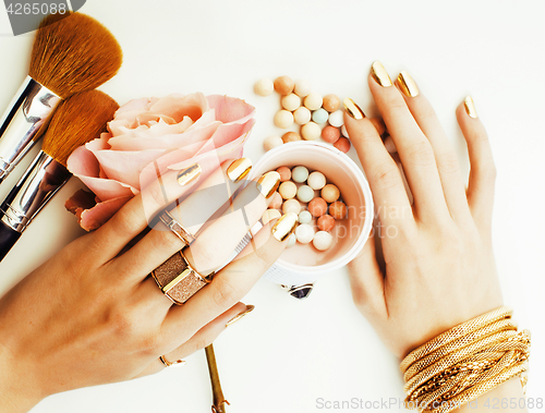 Image of woman hands with golden manicure and many rings holding brushes,